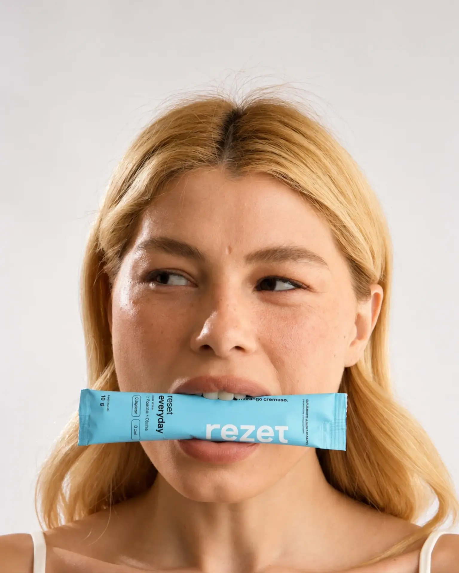 Mulher com um sachê azul rezet entre os dentes